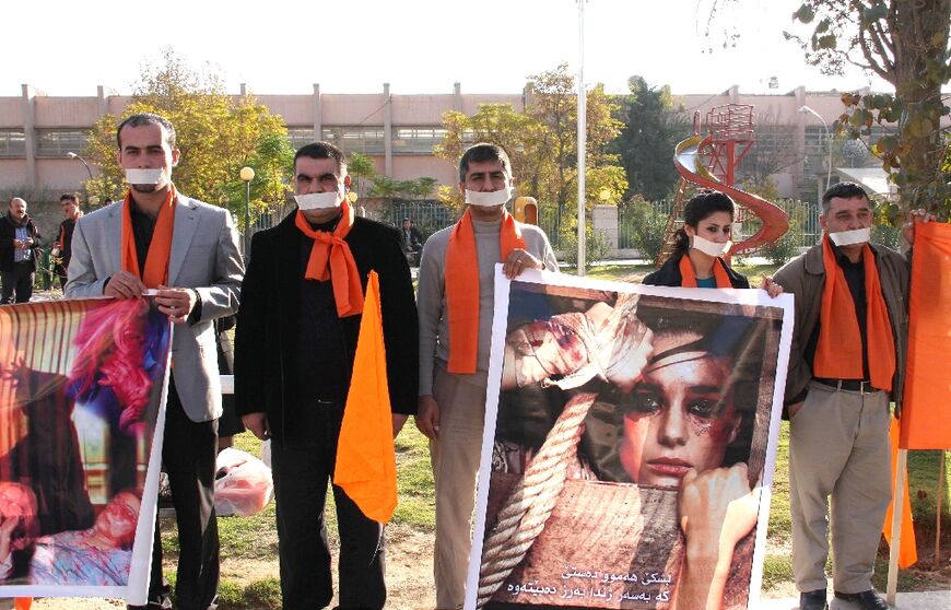 In this file photo taken on November 25, 2008 in Sulaimaniyah, Iraqi Kurds with their mouth plastered shut hold posters showing abused women as they mark the International Day for the Elimination of Violence Against Women