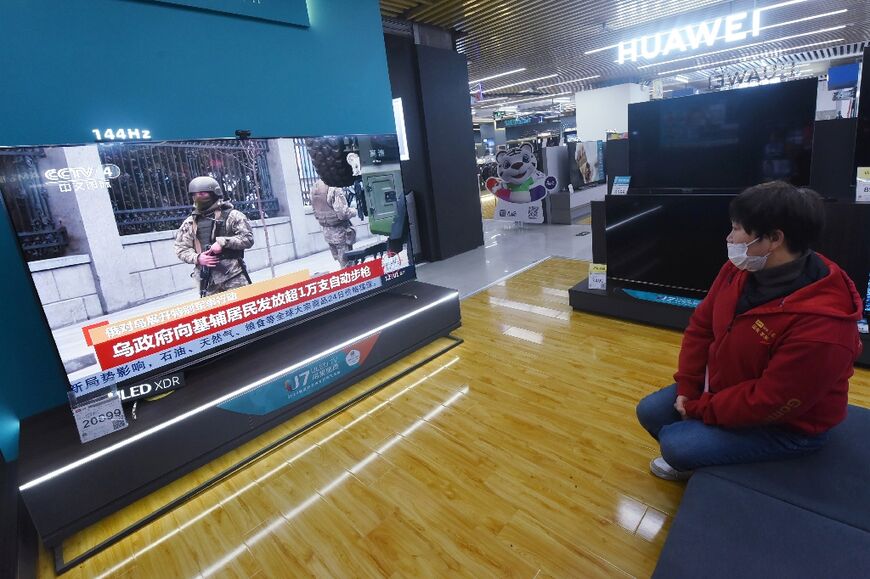 A resident watches TV news about the Ukraine conflict at a shopping mall in China's eastern Zhejiang province 