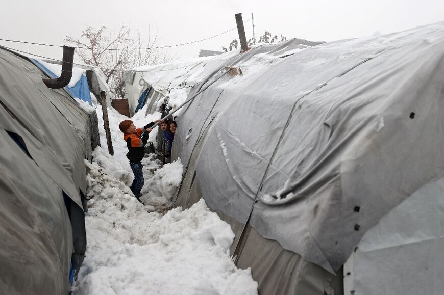 A boy clears snow from a tent at a Syrian camp for the internally displaced near the city of Jisr al-Shughur in the northwestern province of Idlib, on January 26, 2022