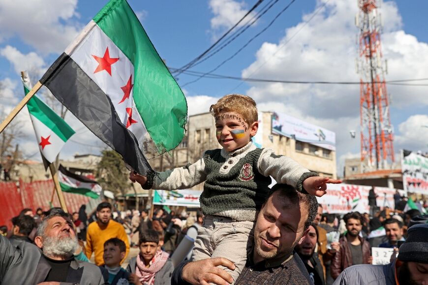 A Syrian boy with his face painted in the colours of the Ukranian flag attends the rally in Idlib