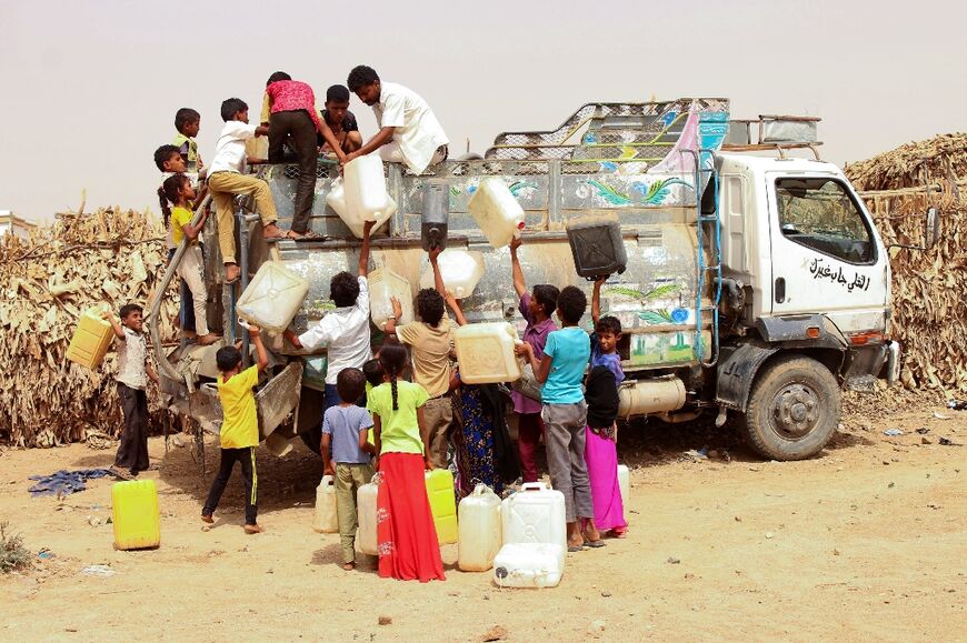 Displaced Yemenis from Hodeida fill jerrycans with water at a make-shift camp in the northern district of Abs