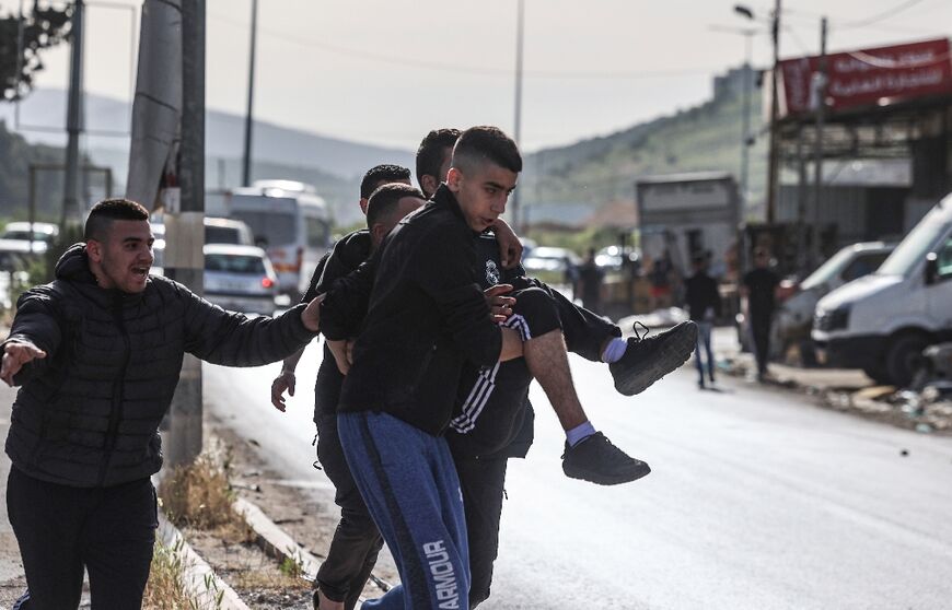 Palestinians carry a wounded man following a raid by Israeli troops in the Nur Shams refugee camp near in the northern West Bank town of Tulkarem on April 10