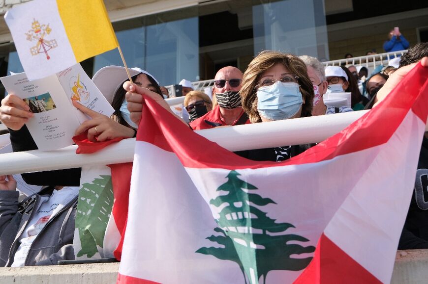 A Lebanese worshipper holds the flags of Lebanon and the Vatican during a mass by Pope Francis in Nicosia, Cyprus on December 3, 2021