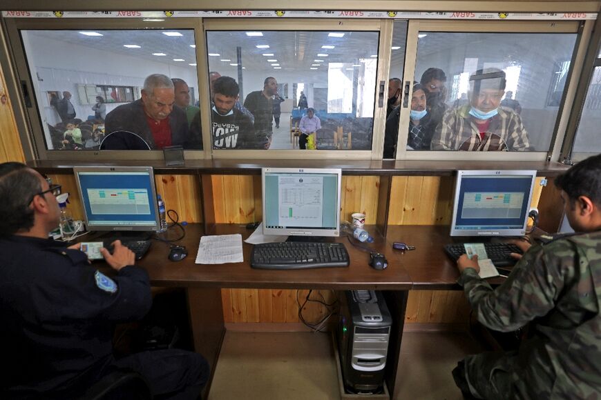 Officers check documents of workers waiting to reach Israel through the Erez crossing following its reopening, in Beit Hanun in the northern Gaza Strip on April 26, 2022