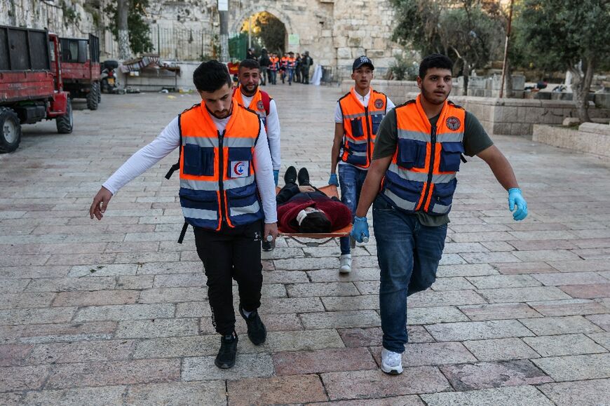 Rescuers evacuate an injured man as Palestinian demonstrators and Israeli police clash