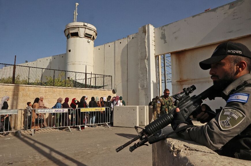 Israeli security forces at Bethlehem, in the occupied West Bank, keep watch on Palestinians crossing a checkpoint to reach Jerusalem for the last Friday prayers of Ramadan at the Al-Aqsa mosque compound