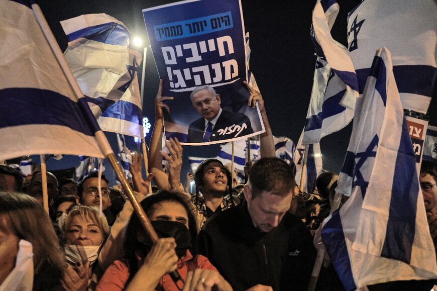 Israeli right-wing demonstrators raise signs showing the face of former prime minister and current leader of the opposition Benjamin Netanyahu during an anti-government protest in Jerusalem