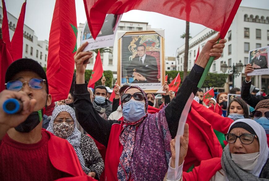 Moroccans celebrate in front of the parliament building in Rabat on December 13, 2020, after the US adopted a new official map of Morocco that includes the disputed territory of Western Sahara