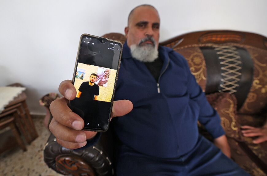 A Palestinian man displays a picture of his nephew Raad Hazem, 28, a Palestinian gunman who killed two people and wounded several others in Tel Aviv the previous night, on April 8, 2022 in the West Bank city of Jenin