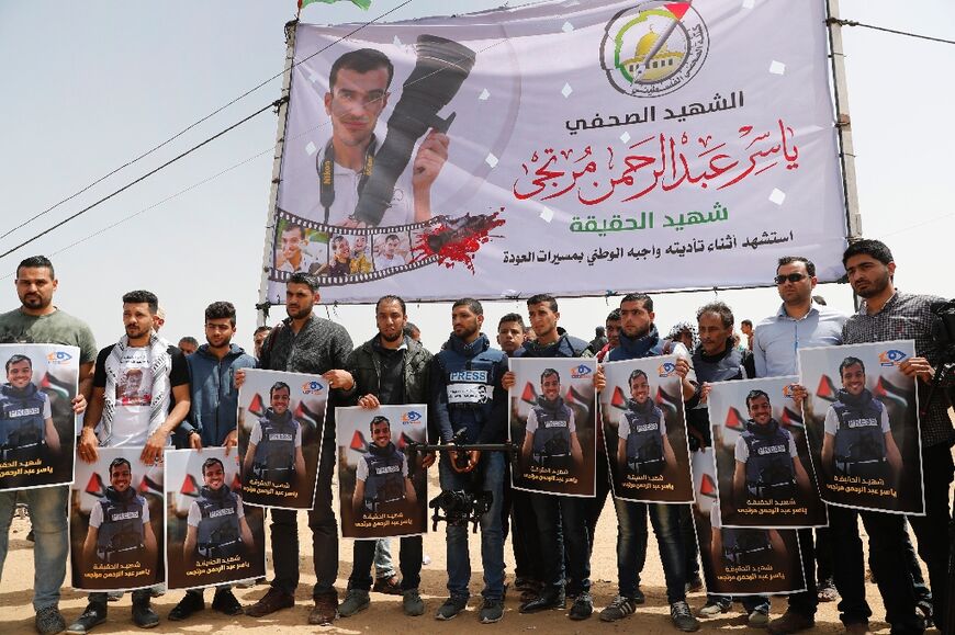 Palestinians hold portraits of Yasser Murtaja, a Gaza reporter killed by Israeli fire, during a protest at the border fence with Israel, east of Khan Yunis in the southern Gaza city, on April 13, 2018