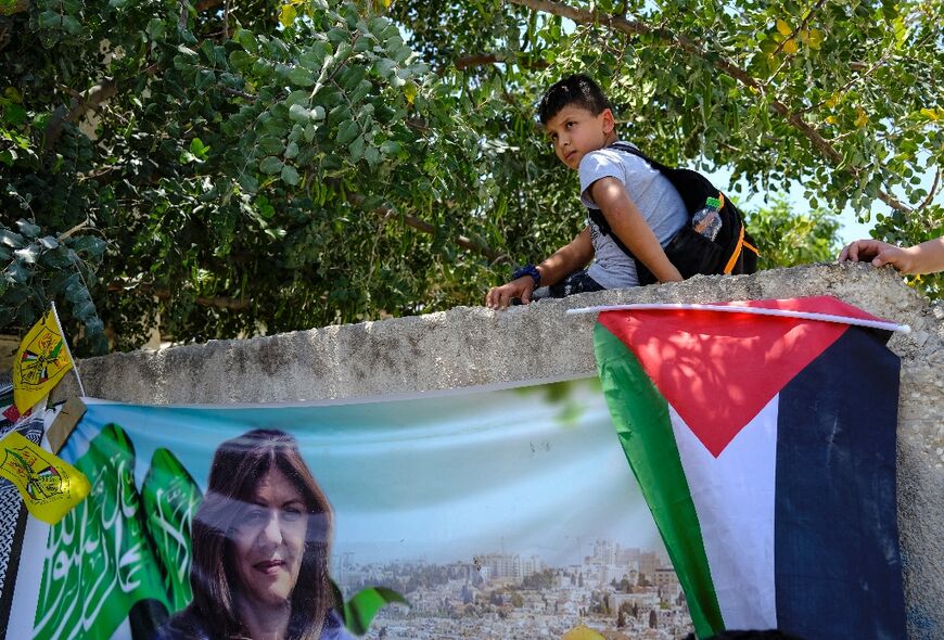 A schoolboy sits on a wall above a Palestinian flag in Jenin in the occupied West Bank