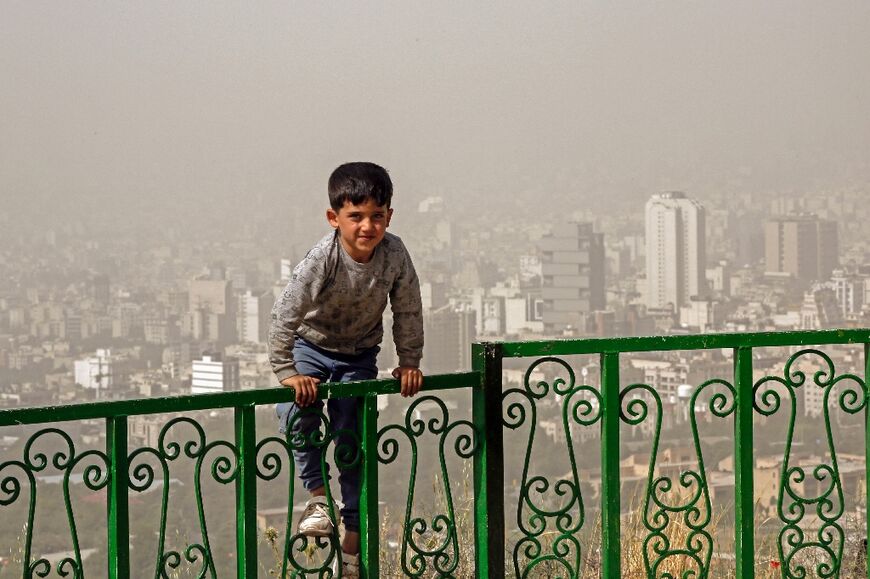 A boy plays outside during a heavy sandstorm in the north of Iran's capital Tehran on May 17, 2022