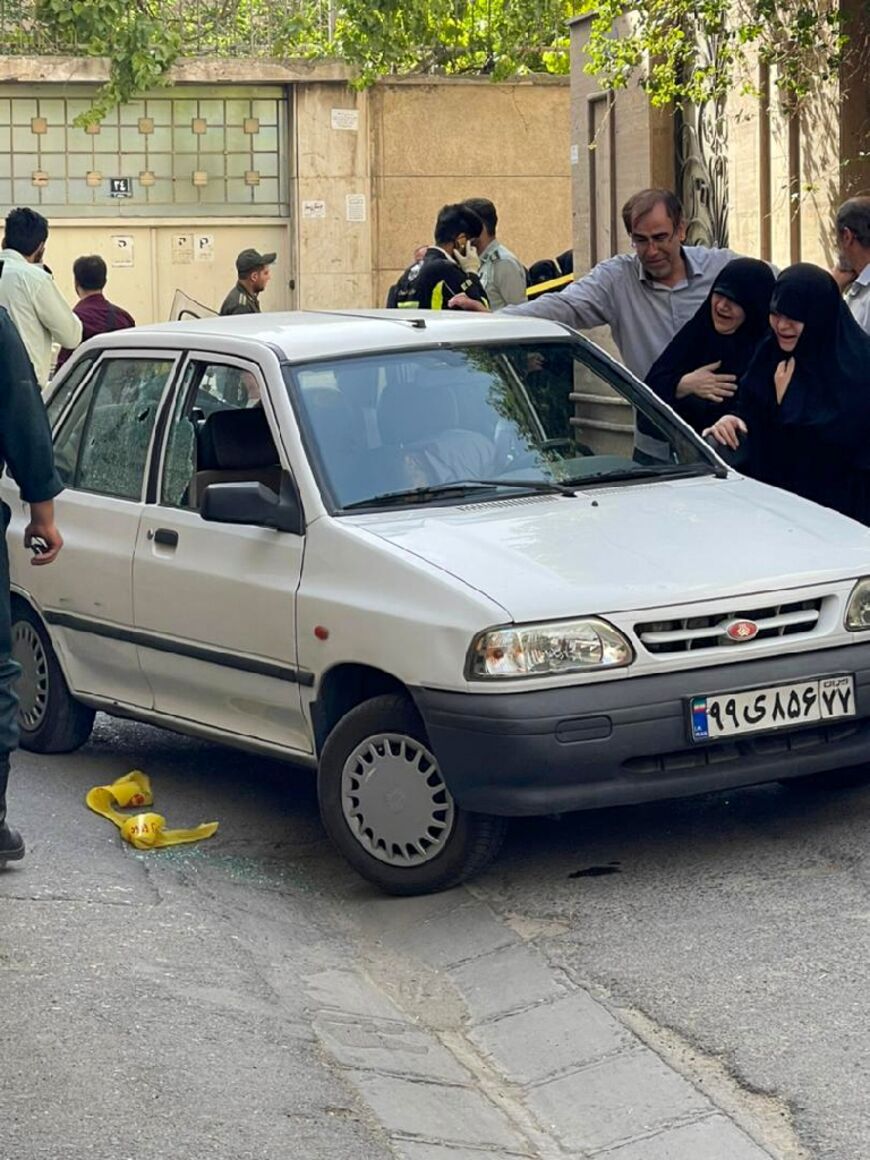 A picture shows two women mourning next to the body of Iranian Revolutionary Guards colonel Sayyad Khodai, after he was shot dead, in his car in the Iranian capital Tehran on May 22, 2022