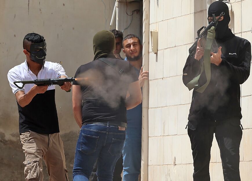 A masked Palestinian man fires an automatic weapon during the latest clashes with Israeli security forces in the West Bank city of Jenin