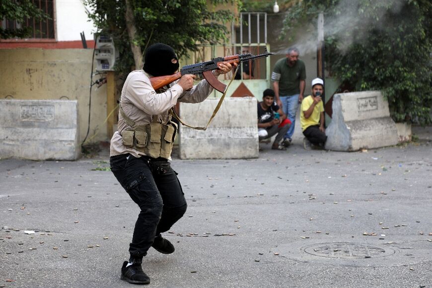 A Lebanese Shiite fighter takes aim with a Kalashnikov amid clashes in the Tayouneh suburb of Beirut, on October 14, 2021