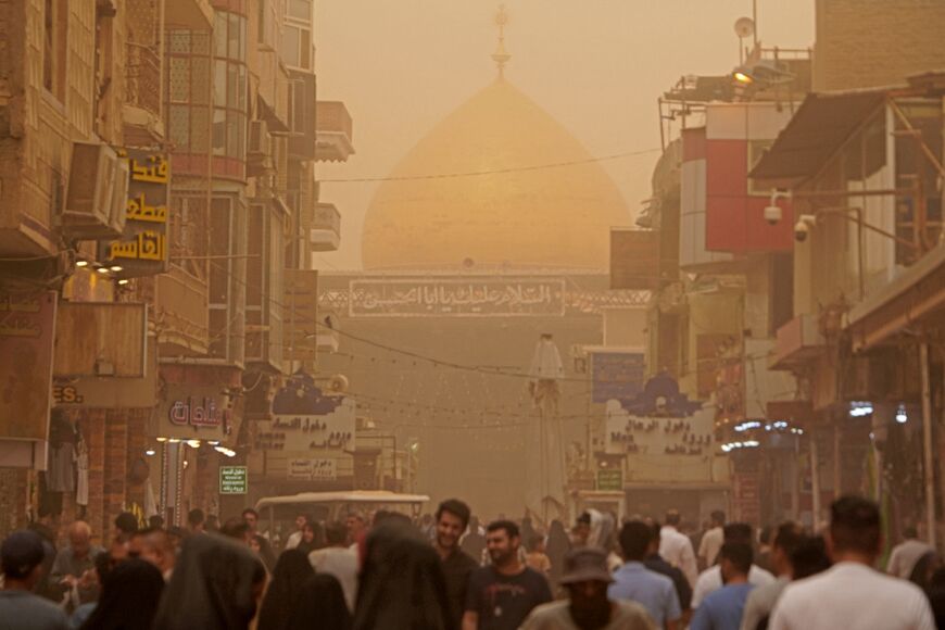 Iraqis walk outside the Imam Ali shrine during a sandstorm in Iraq's holy city of Najaf on May 5, 2022