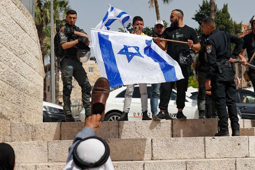 A Palestinian man raises a shoe in an Arab insult against Israelis waving their national flags at Jerusalem Gate, ahead of the controversial "flag march"