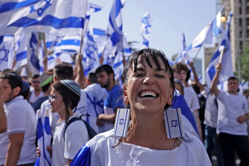 A woman wearing earrings depicting the Israeli flag smiles ahead of the 'flags march' 