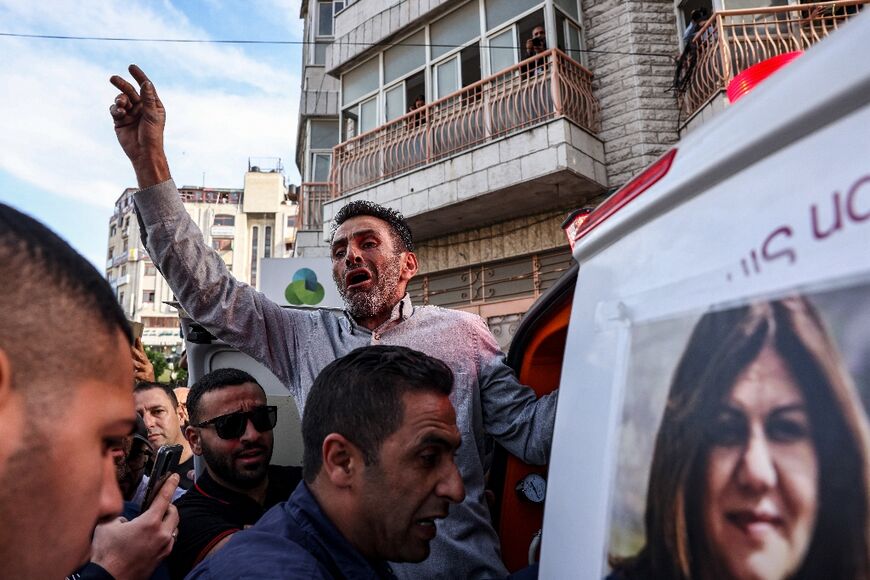 A Palestinian man reacts as the body of veteran Al-Jazeera journalist Shireen Abu Akleh is carried toward the offices of the news channel in the West Bank city of Ramallah