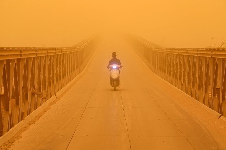A motorist drives a scooter along a bridge in the city of Nasiriyah in Iraq's southern Dhi Qar province on May 16, 2022 amidst a heavy dust storm