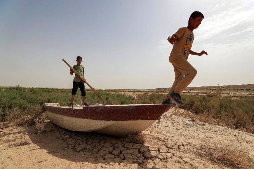 Iraqi children play on a boat grounded by the shrinking of Lake Hamrin -- the reservoir once provided fish for the dinner table as well as water for irrigation