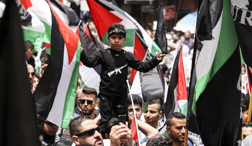 Palestinians wave flags as they march to mark the 74th anniversary of the "Nakba" or "catastrophe", in the occupied West Bank town of Ramallah, on May 15