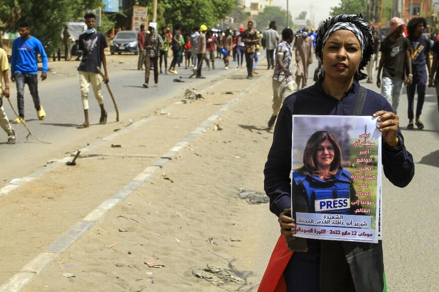 A Sudanese demonstrator carries a poster of slain Al Jazeera journalist Shireen Abu Akleh