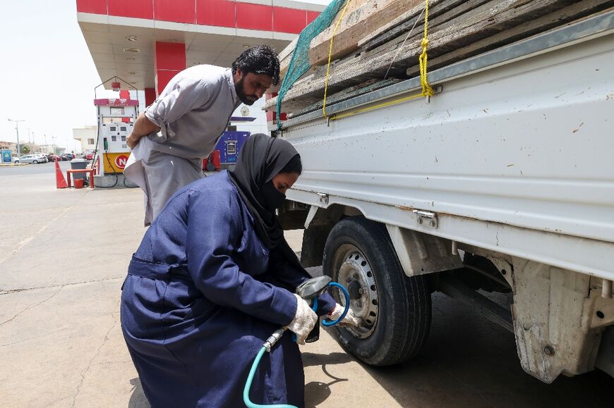 A male customer watches over Ghada Ahmed as she works on his truck