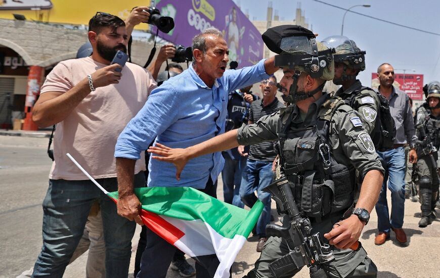 A man holding a Palestinian flag scuffles with Israeli border guards in the occupied West Bank town of Huwara, on May 27, 2022