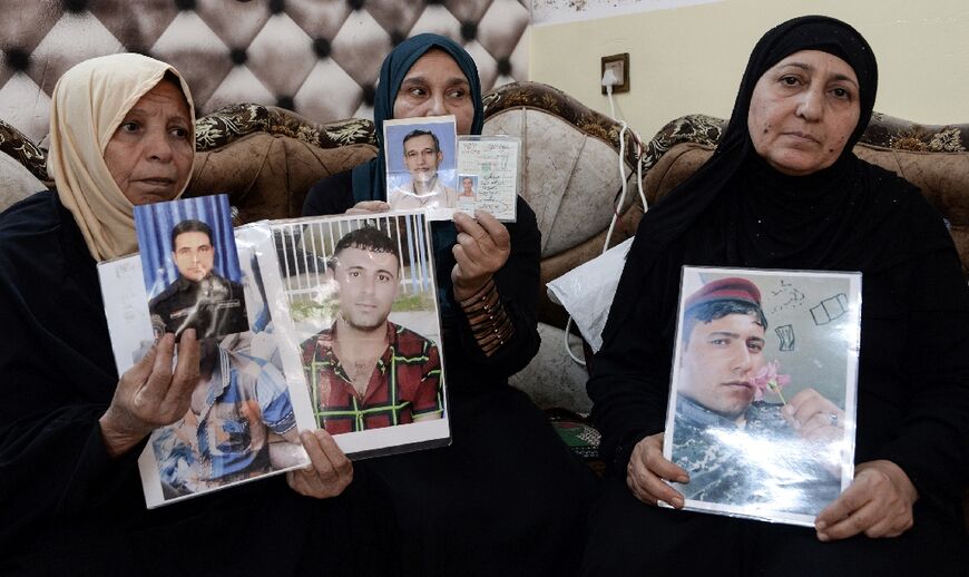 Women hold pictures of their missing sons at the home of Um Ahmed in the northern Iraqi city of Mosul