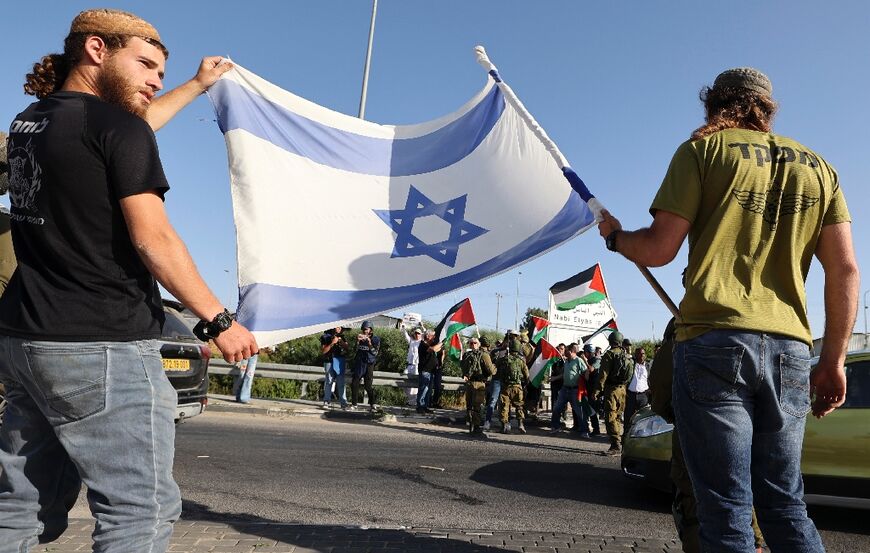 Israeli security forces stand between Jewish settlers and Palestinians, accompanied by Israeli and foreign activists, each side carrying their flags, east of the occupied West Bank town of Qalqiliya, on May 9 2022