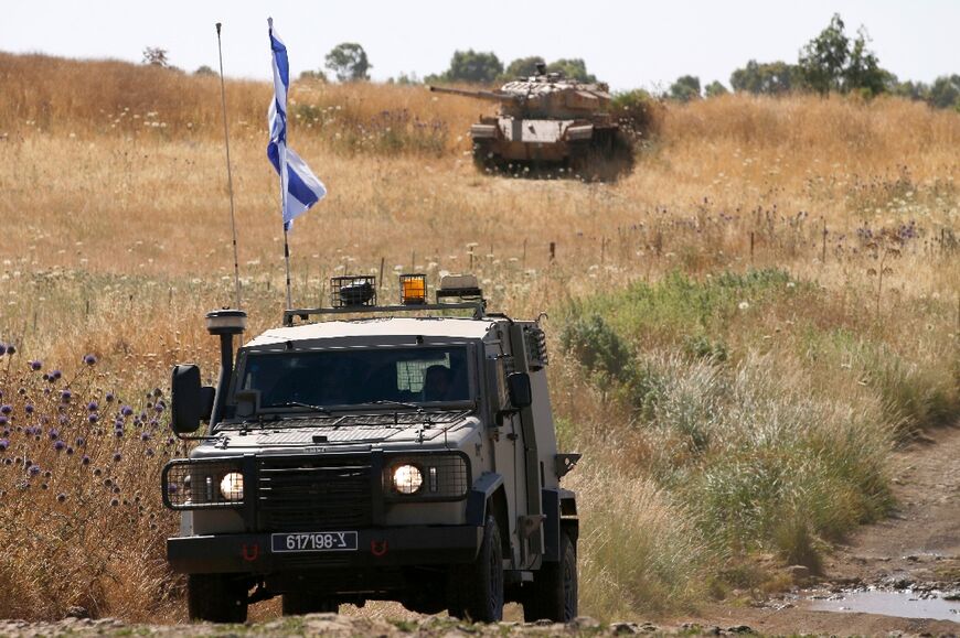An Israeli military jeep patrols the border with Syria, in front of a tank abandoned from the 1967 war, in the Israeli-annexed Golan Heights from where, Syrian state media said, a volley of missiles was fired and some struck Damascus airport