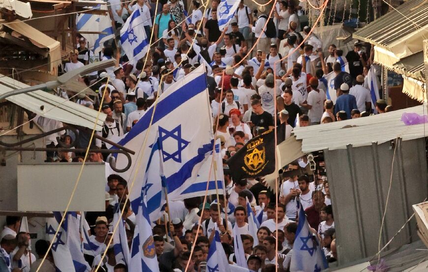 Demonstrators waving the Israeli flag and the banner of the far-right Jewish group "Lehava" (Flame) gather during the Israeli 'flags march' to mark "Jerusalem Day" in the Old City on May 29, 2022