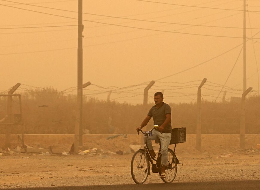 A man rides his bicycle during a sandstorm in the town of Khalis, in Iraq's Diyala province, on July 3