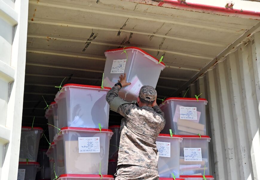 A soldier loads a truck with ballot boxes to be transported to a counting centre in the capital Tunis