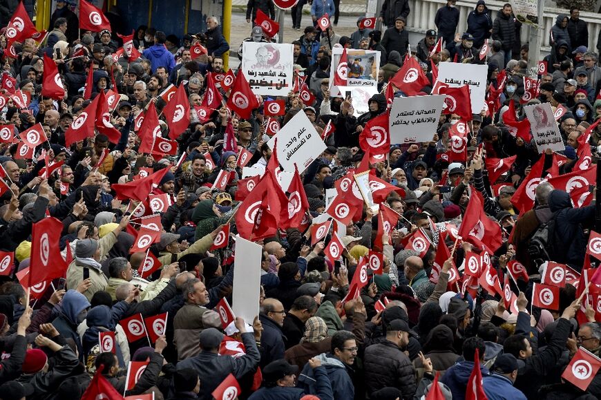 Tunisian protesters raise placards and national flags during a demonstration against their president in the capital Tunis, on March 20