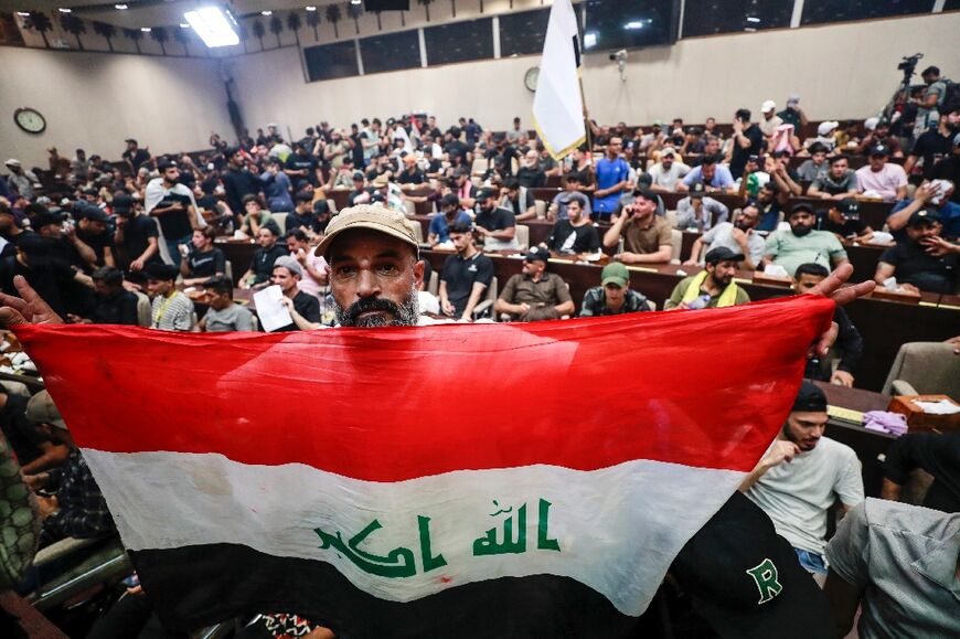 A man displays an Iraqi flag while supporters of the cleric Moqtada Sadr occupy the country's parliament 