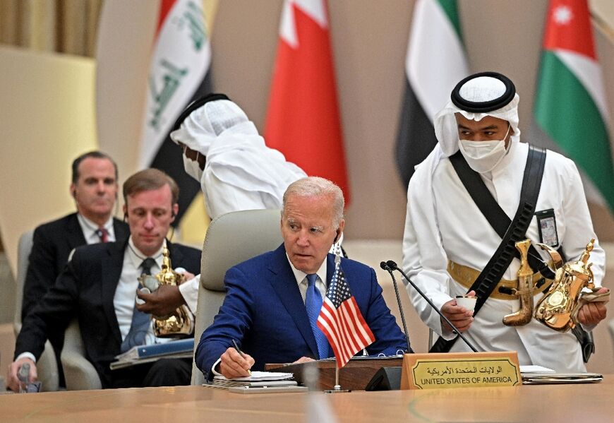 Biden takes notes while an usher serves coffee during the Jeddah summit