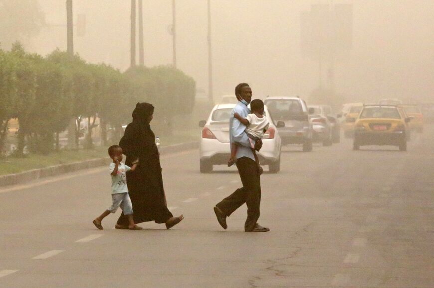 A family crosses a street during a sandstorm in the Iraqi capital Baghdad on July 3: over the next two decades, Iraq  can expect 272 dusty days per year, projected to surpass the 300-day mark by mid-century