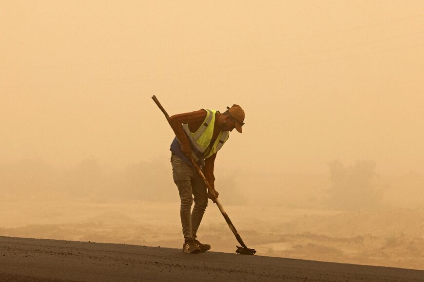 A worker sweeps a road during a sandstorm in Iraq's Diyala province, on July 3: oil-rich Iraq is ranked one of the five countries most vulnerable to the impacts of climate change and desertification