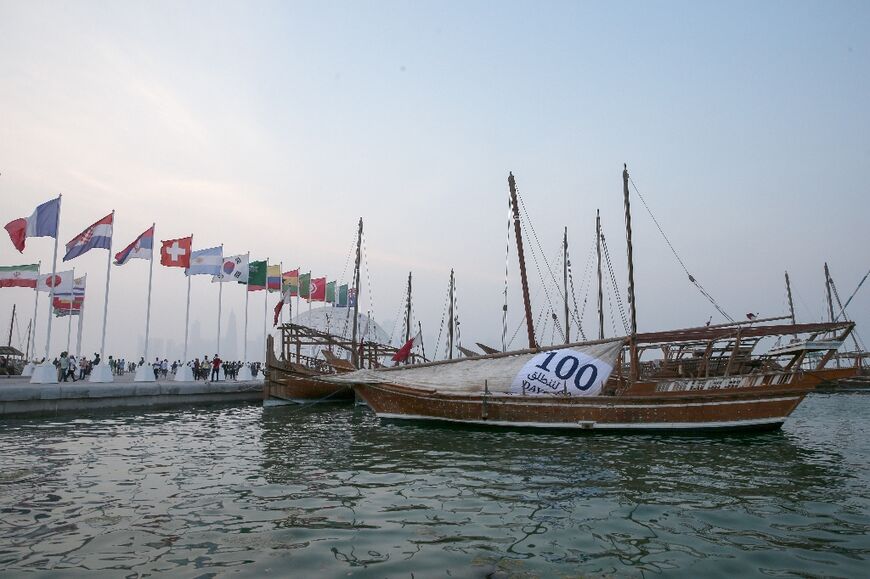 A traditional Qatari sailing vessel known as dhow, with a banner attached to a sail marking 100 days to the tournament