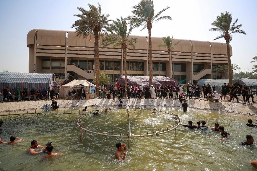 Supporters of Shiite cleric Muqtada al-Sadr cool off outside the Iraqi parliament in the Green Zone in the capital Baghdad, on the seventh day of protests in the Green Zone, on August 5, 2022
