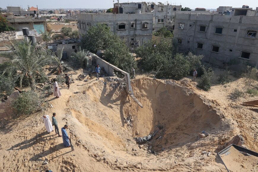 Palestinians inspect a crater following the latest three days of conflict with Israel, in Rafah town in the southern Gaza Strip, on August 8, 2022
