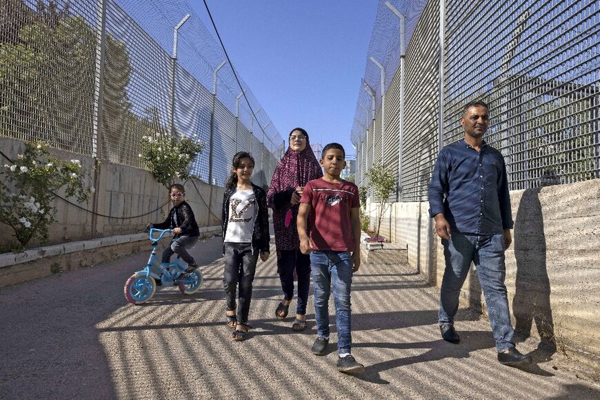 Palestinian Saadat Sabri Gharib (R) walks with his family between Israeli army barriers, toward their house