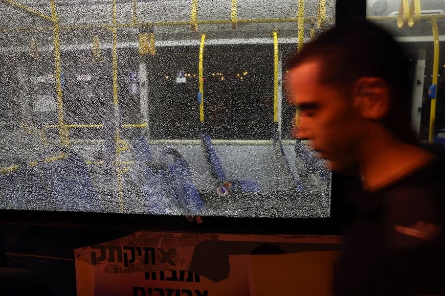 A man walks past a bullet impact in a bus window after an attack outside Jerusalem's Old City, August 14, 2022