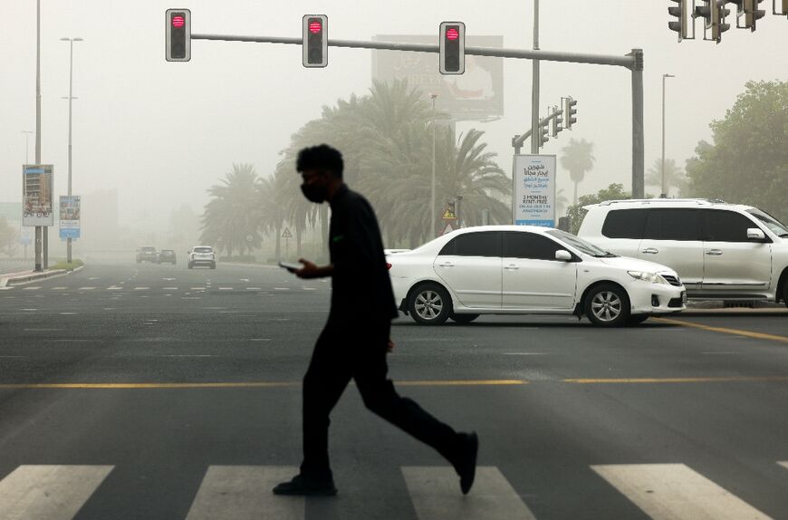 A man crosses a street during a sandstorm in Dubai on August 14, 2022