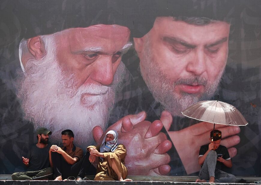 Followers of Sadr, who is shown at right in a portrait in the Baghdad district of Sadr City on June 17, 2022