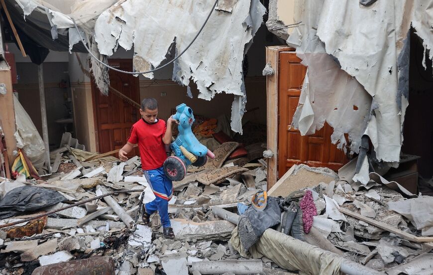 A Palestinian youth salvages a toy from the rubble of his house which was destroyed during three days of conflict with Israel ahead of a truce, in Rafah town in the southern Gaza Strip, on August 8, 2022