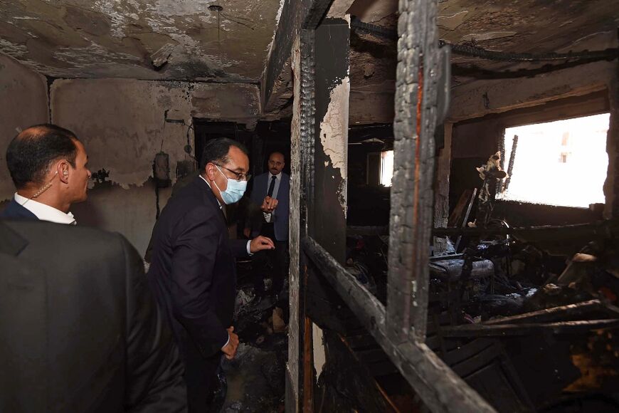 Egypt's Prime Minister Mostafa Madbouli (C) visits the charred remains of Abu Sifin Coptic church after the deadly fire