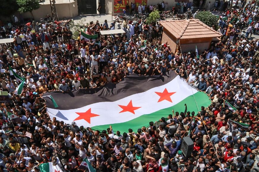 Syrians deploy a large opposition flag as they gather to protest against a proposal from the Turkish foreign minister in the border town of Azaz in the rebel-held north of the Aleppo province